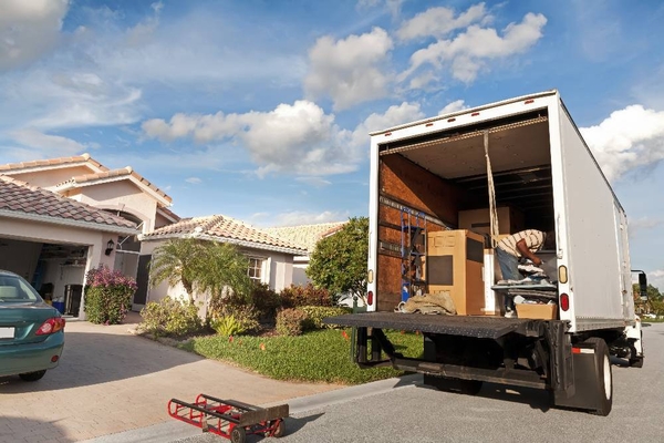 Mover organizing boxes in a truck outside a residential home